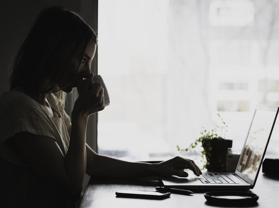 ung kvinde drikker kaffe, studerer på en bærbar computer